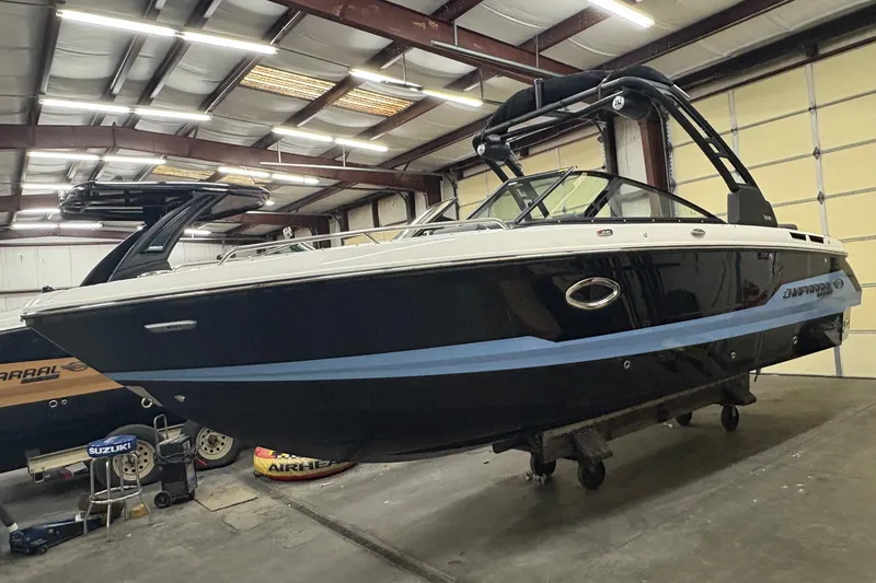 Slide: The Image of 2025 Chaparral 26 Surf boat in a warehouse, showcasing sleek design and modern features. - 2