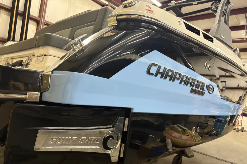 Slide: The Image of 2025 Chaparral 26 Surf boat in showroom, featuring sleek design and Surf Gate technology. - 3