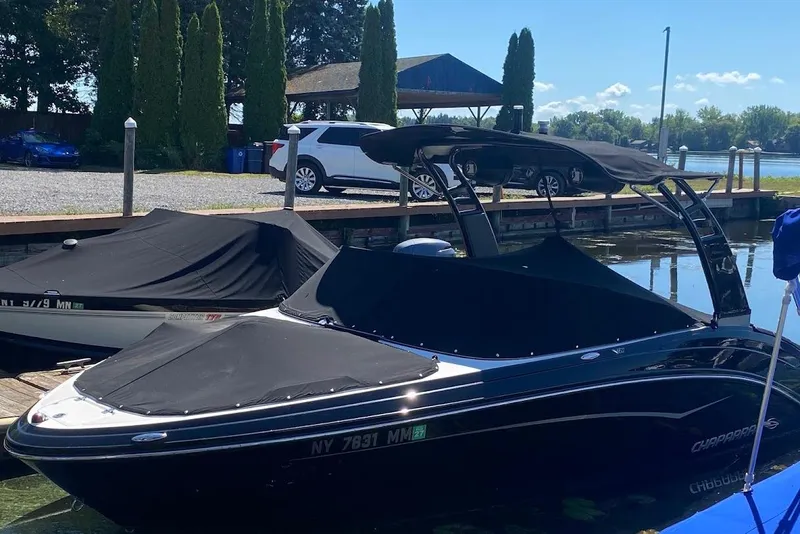 Slide: The Image of 2017 Chaparral Vortex 203 VR boat docked, covered, with trees and cars in the background. - 2