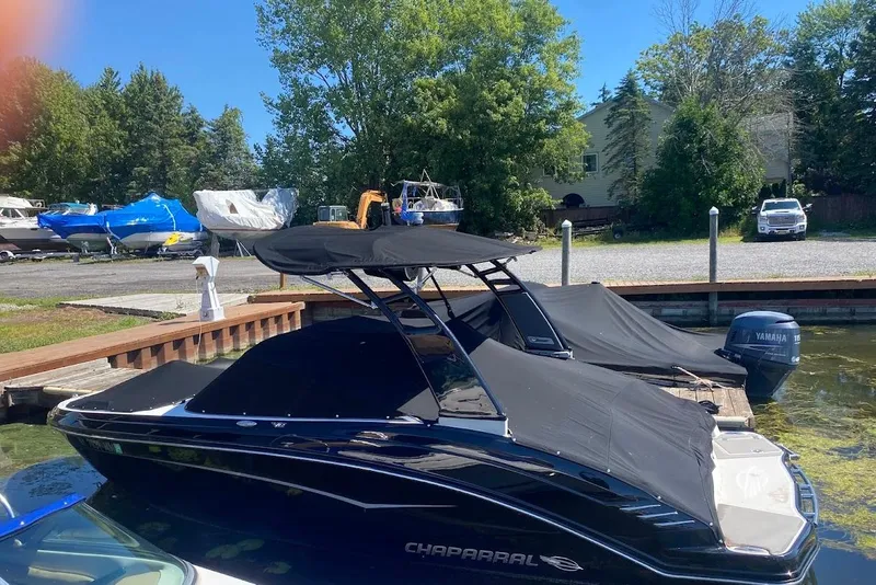Slide: The Image of 2017 Chaparral Vortex 203 VR boat docked with cover, surrounded by trees and parked vehicles. - 3