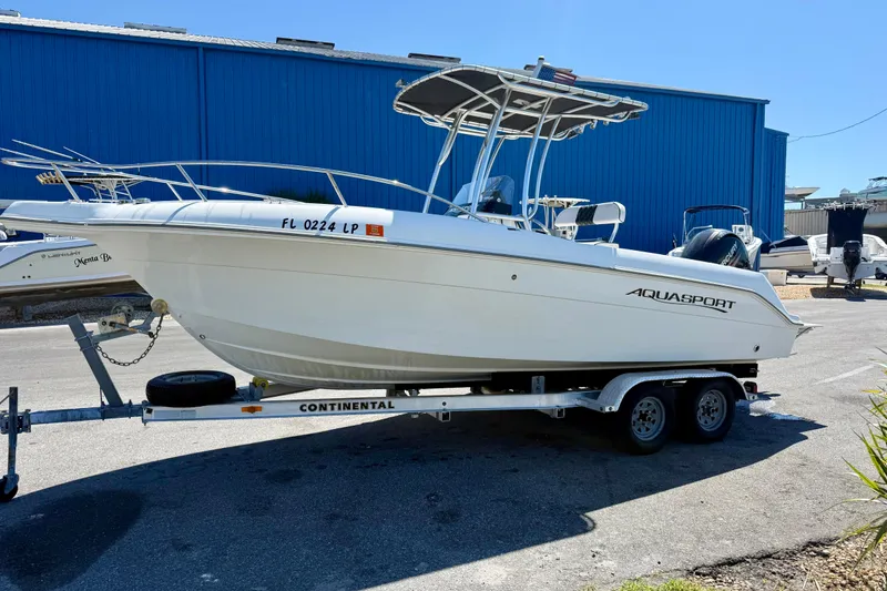 Slide: The Image of 2001 Aquasport 205 Osprey boat on trailer, parked near blue building. - 10