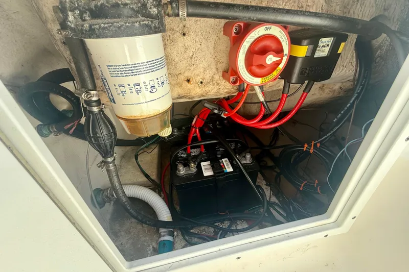 Slide: The Image of 2001 Aquasport 205 Osprey boat battery compartment with wiring and filter system. - 26