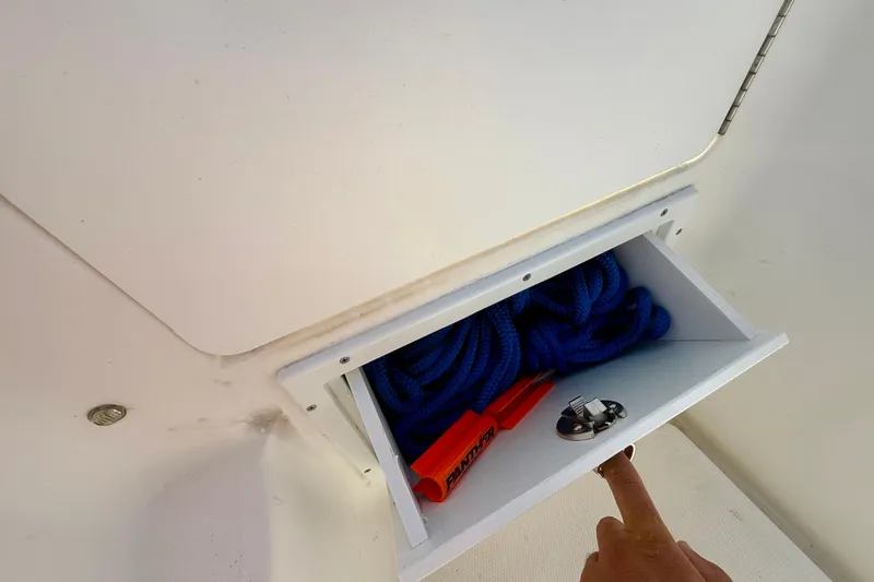 Slide: The Image of Storage compartment on a 2001 Aquasport 205 Osprey boat with blue rope and safety equipment. - 28