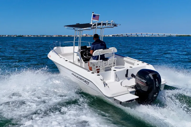 Slide: The Image of 2001 Aquasport 205 Osprey boat cruising on open water with bridge in background. - 3