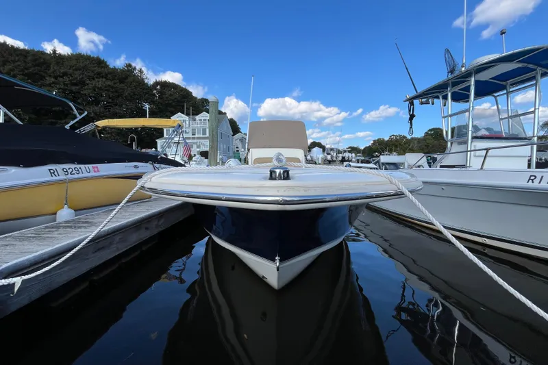 Slide: The Image of 2020 Scout 195 Sportfish boat docked between two others under a clear blue sky. - 1