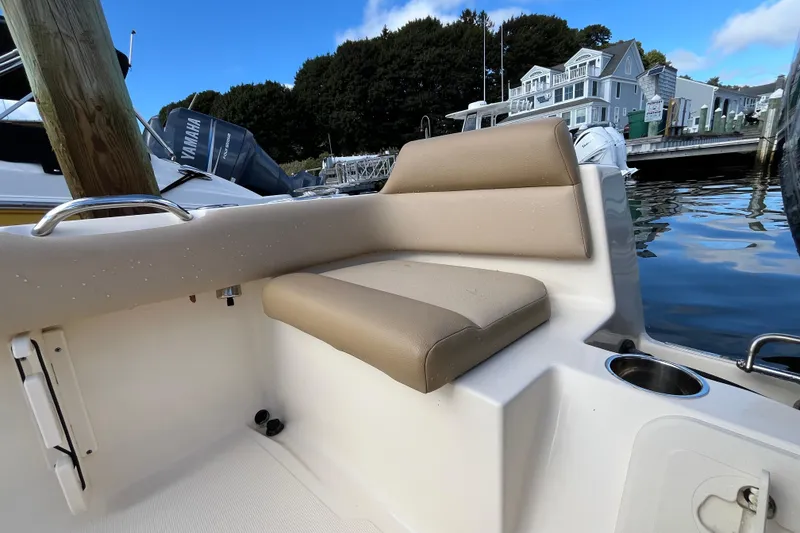 Slide: The Image of 2020 Scout 195 Sportfish boat interior with beige seating and cup holder, docked by waterfront homes. - 31