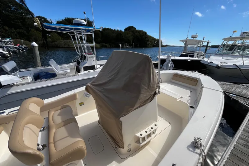 Slide: The Image of 2020 Scout 195 Sportfish boat docked, featuring beige seating and covered console. - 36