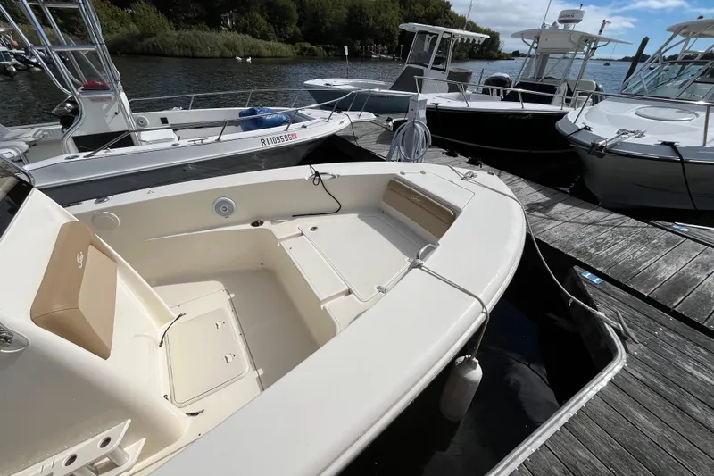 Slide: The Image of 2020 Scout 195 Sportfish boat docked at marina, featuring spacious seating and sleek design. - 4