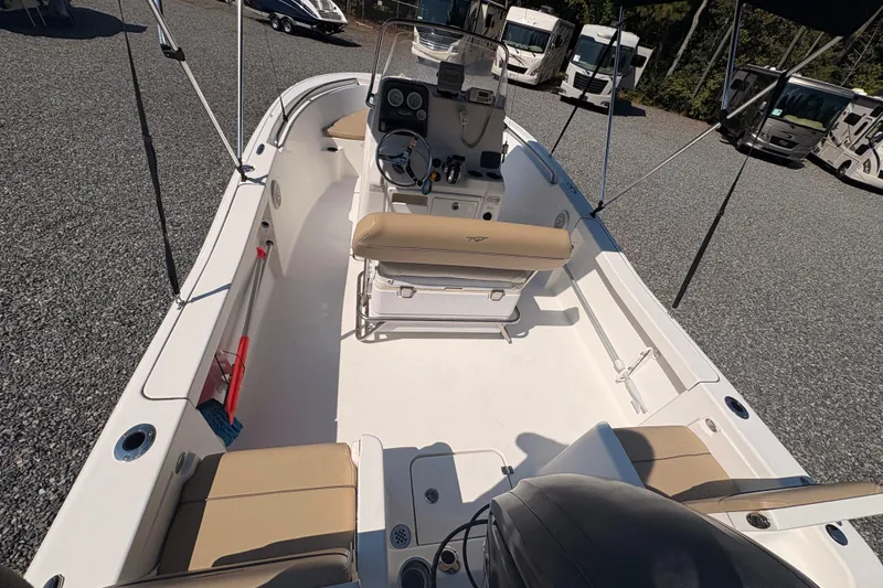 Slide: The Image of 2015 Tidewater 198 CC Adventure boat interior with seating and console, parked on gravel. - 11