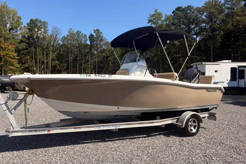 The Image of 2015 Tidewater 198 CC Adventure boat on trailer, parked outdoors with trees in background. - 6