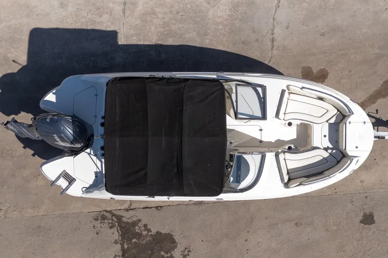 Slide: The Image of 2024 Stingray 211DC boat, aerial view, black cover, white seating, outboard motor. - 17