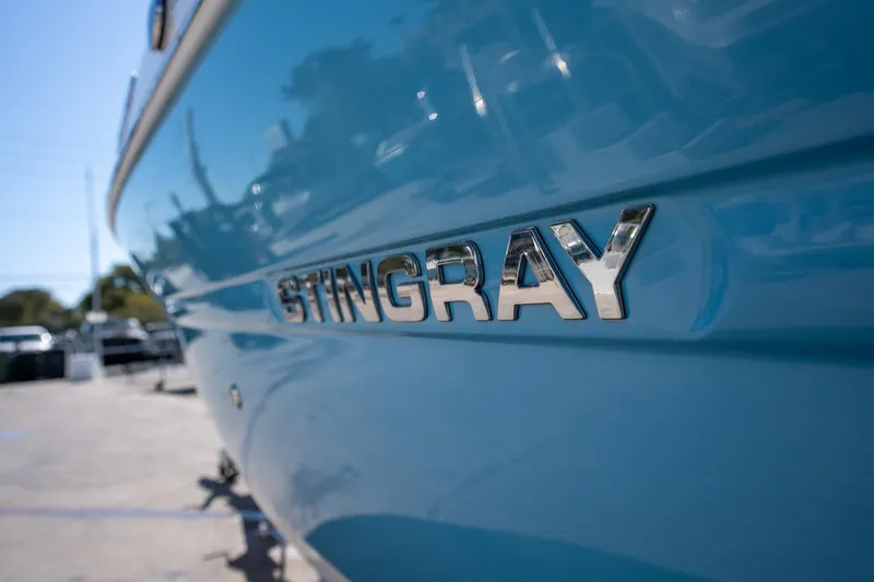 Slide: The Image of 2024 Stingray 211DC boat with chrome logo on blue hull. - 3