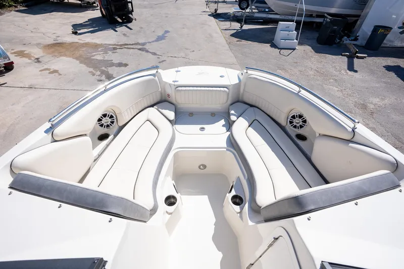 Slide: The Image of 2024 Stingray 211DC boat interior with white seating and speakers, docked outdoors. - 6
