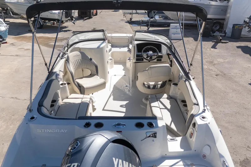 Slide: The Image of 2024 Stingray 211DC boat interior with seating and steering wheel, docked outdoors. - 7