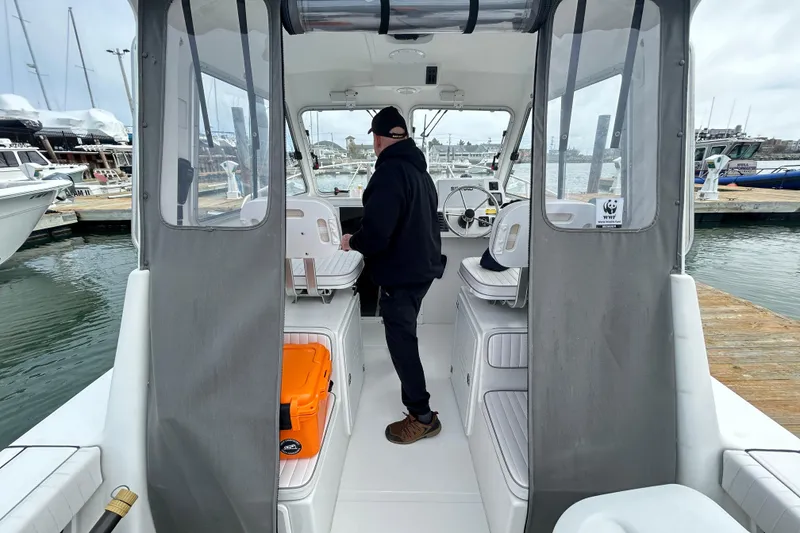 Slide: The Image of 2020 Maritime 23 Challenger boat interior with person at helm, docked at marina. - 10