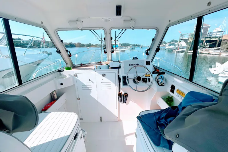Slide: The Image of Interior of 2020 Maritime 23 Challenger boat with steering wheel, windows, and waterfront view. - 14
