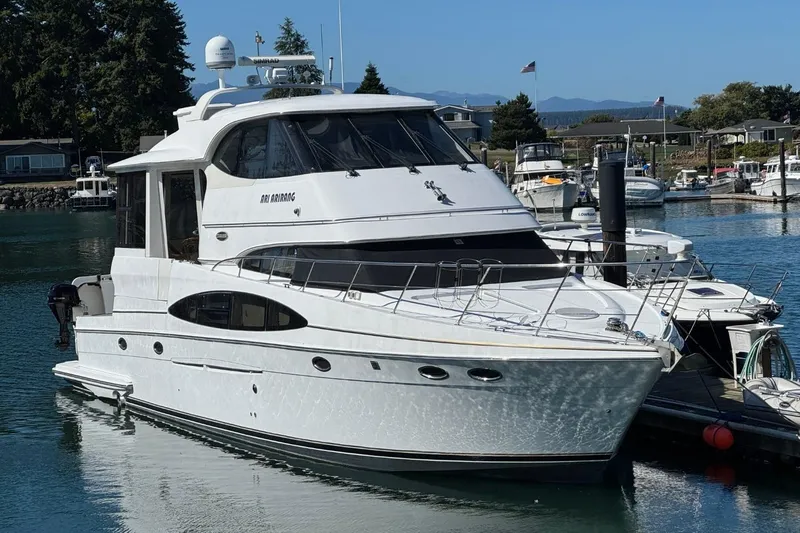 Slide: The Image of 2004 Carver 564 Cockpit Motor Yacht docked in a marina, surrounded by other boats. - 2