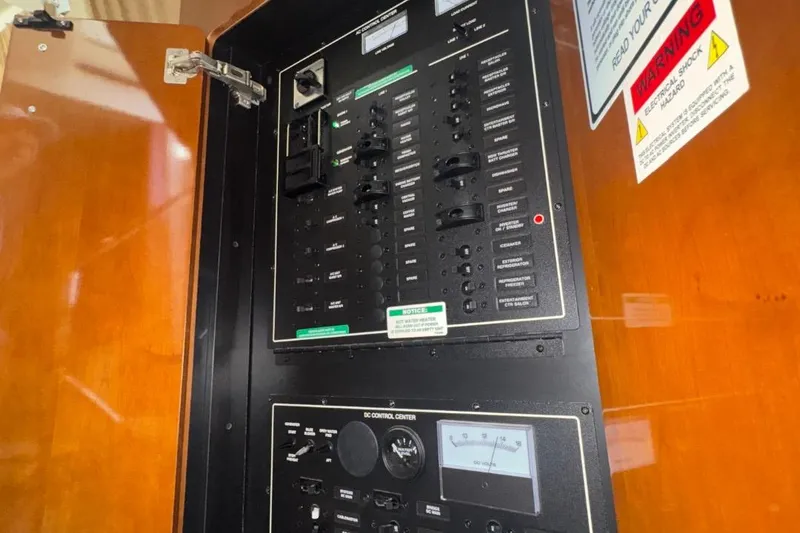 Slide: The Image of Electrical control panel inside 2004 Carver 564 Cockpit Motor Yacht, featuring switches and warning labels. - 52