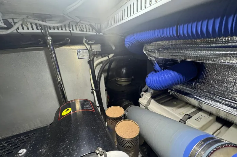 Slide: The Image of Engine room of 2004 Carver 564 Cockpit Motor Yacht with blue hoses and filters. - 72