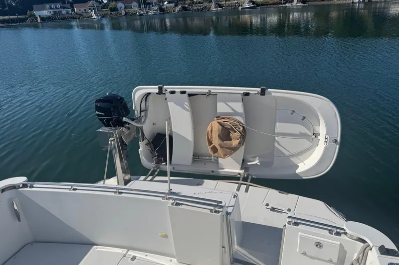 Slide: The Image of 2004 Carver 564 Cockpit Motor Yacht with dinghy and outboard motor on calm water. - 79