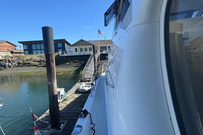 Slide: The Image of 2004 Carver 564 Cockpit Motor Yacht docked near modern waterfront homes. - 9