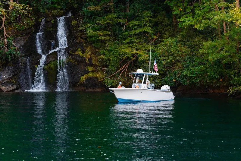Slide: The Image of 2026 Sportsman Heritage 231 Center Console boat near a scenic waterfall and lush greenery. - 23