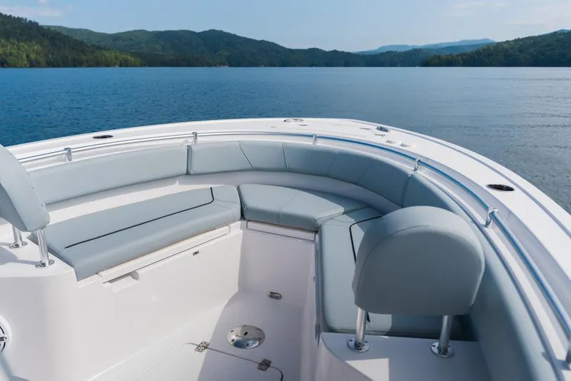 Slide: The Image of 2026 Sportsman Heritage 231 Center Console boat interior with cushioned seating on a serene lake. - 28