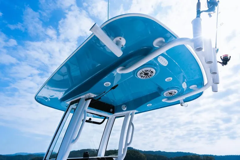 Slide: The Image of 2026 Sportsman Heritage 231 Center Console boat with blue T-top against a cloudy sky. - 32