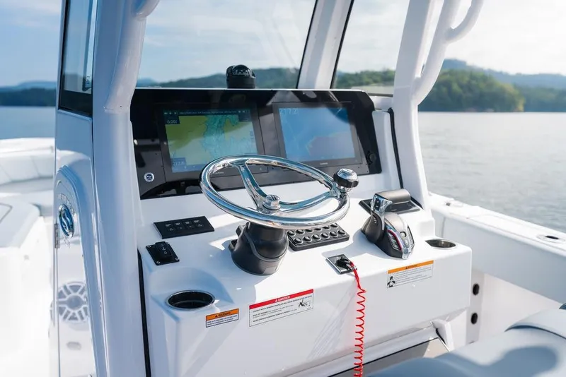 Slide: The Image of 2026 Sportsman Heritage 231 Center Console boat dashboard with steering wheel and navigation screens. - 33
