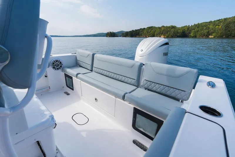 Slide: The Image of 2026 Sportsman Heritage 231 Center Console boat interior with cushioned seating on a serene lake. - 37
