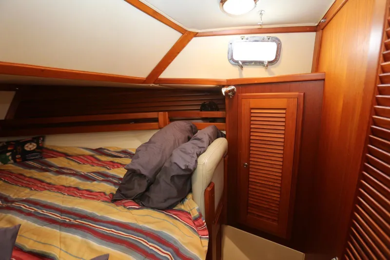 Slide: The Image of Cozy cabin interior of 2004 Pacific Seacraft 40 sailboat with striped bedding and wooden paneling. - 12