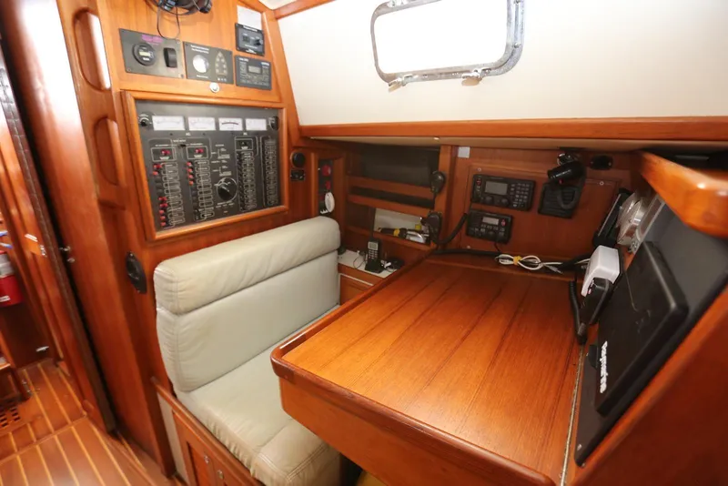 Slide: The Image of Navigation station inside 2004 Pacific Seacraft 40 sailboat, featuring control panels and wooden desk. - 19