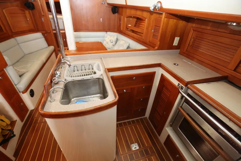 Slide: The Image of Interior of 2004 Pacific Seacraft 40 sailboat, featuring a compact kitchen with wooden cabinetry. - 26