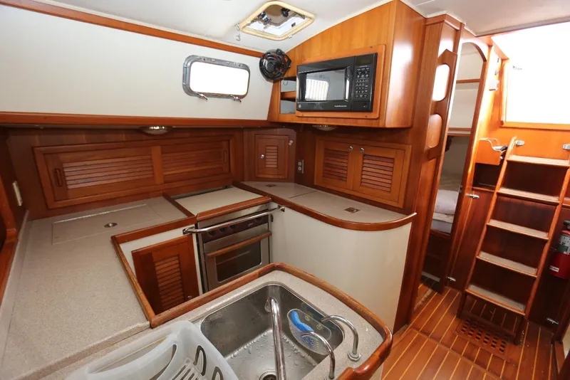 Slide: The Image of Interior of 2004 Pacific Seacraft 40 sailboat, featuring a well-equipped wooden galley kitchen. - 35