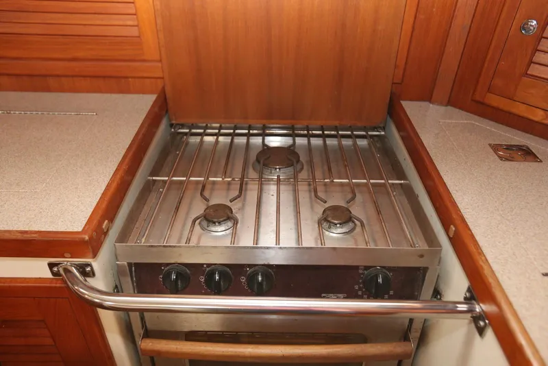 Slide: The Image of Stove in 2004 Pacific Seacraft 40 yacht kitchen, featuring three burners and wooden cabinetry. - 39