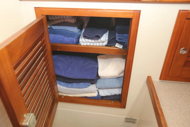 Slide: The Image of Wooden cabinet with neatly stacked towels on a 2004 Pacific Seacraft 40 yacht. - 66
