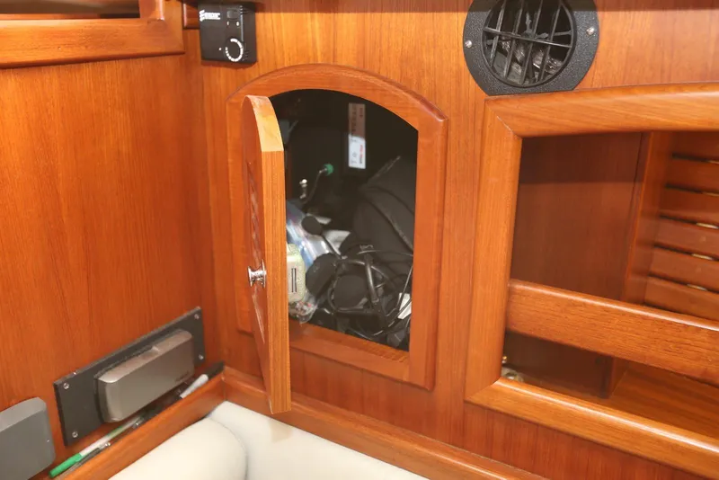 Slide: The Image of Wooden interior cabinet on a 2004 Pacific Seacraft 40 sailboat, partially open with visible contents. - 72