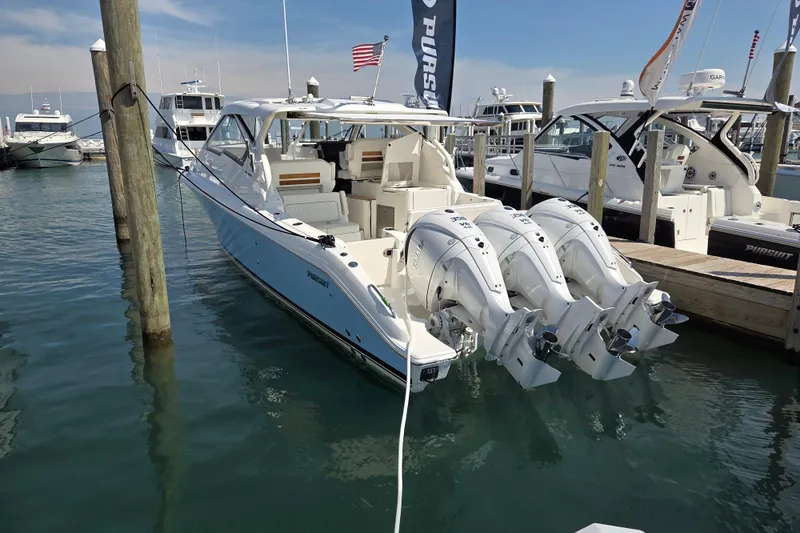 The Image of 2026 Pursuit DC 365 Dual Console boat docked with triple outboard engines. - 0