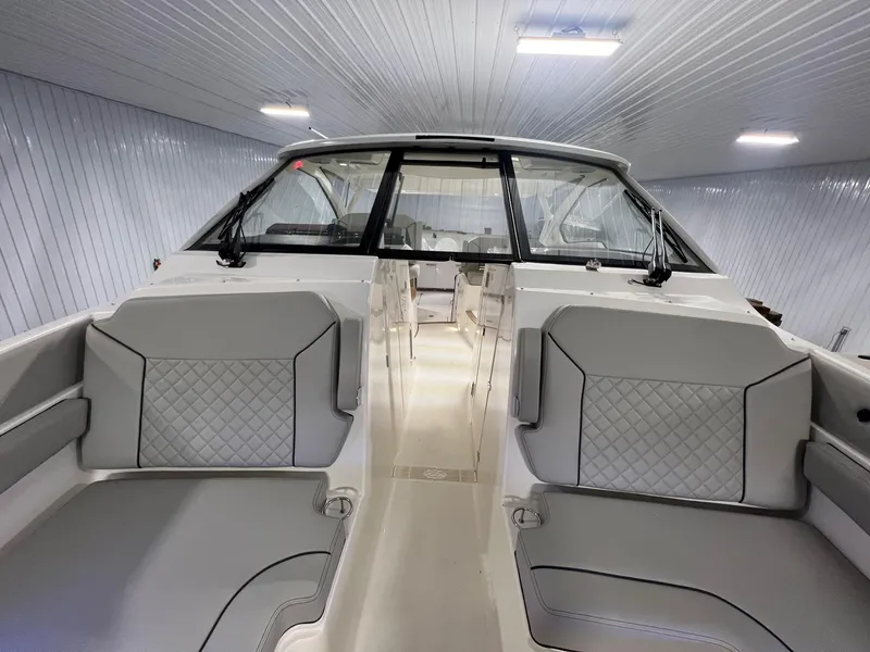 Slide: The Image of 2026 Pursuit DC 365 Dual Console boat interior with gray seating in a well-lit showroom. - 14