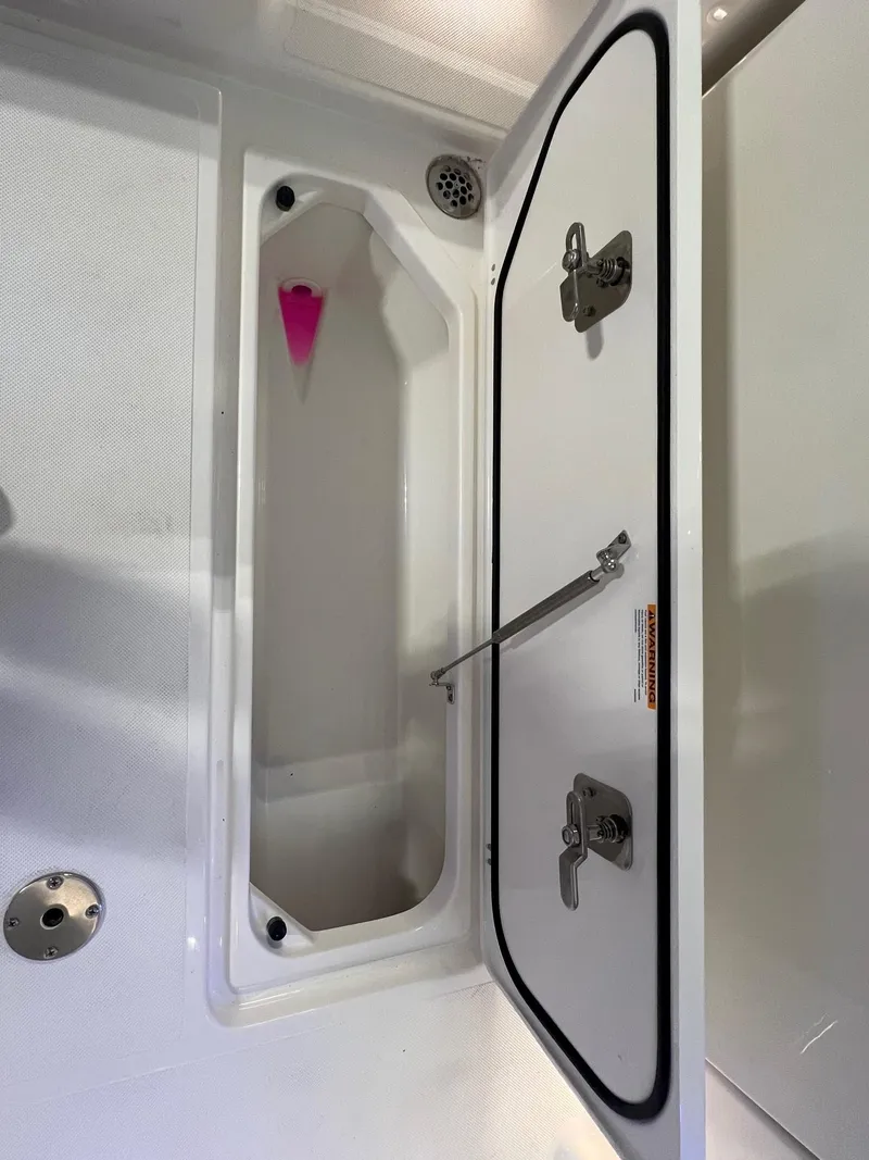Slide: The Image of 2026 Pursuit DC 365 Dual Console storage compartment with open hatch and secure latches. - 8