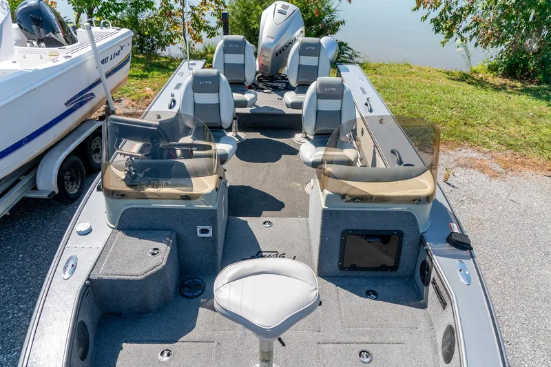 Slide: The Image of 2006 Lund 2025 Pro-V Magnum SE boat interior with seating and controls, parked near water. - 19