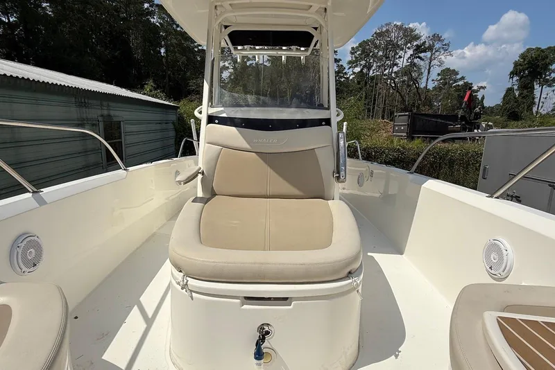 Slide: The Image of 2017 Boston Whaler 270 Dauntless boat interior with seating and console, surrounded by trees. - 9