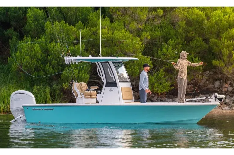 Slide: The Image of Manufacturer Provided Image: 2025 Sportsman Masters 227 Bay Boat on water, two people fishing, lush greenery background. - 2