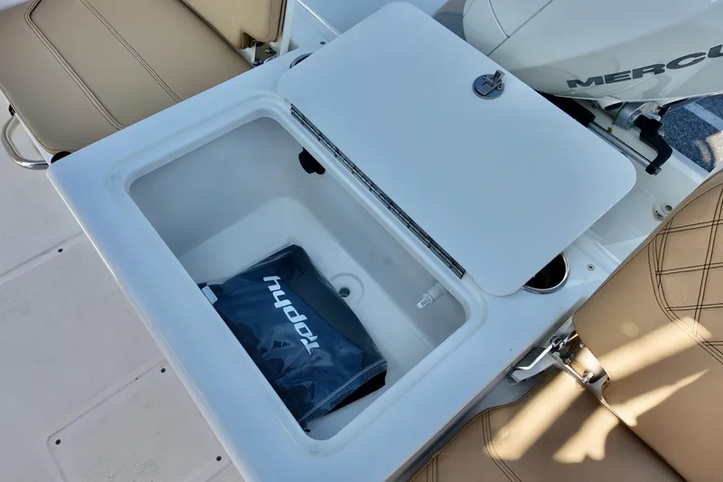 Slide: The Image of 2026 Bayliner Trophy T22CC boat storage compartment with beige seating and Mercury engine. - 12