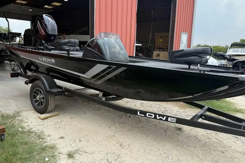 Slide: The Image of 2026 Lowe Skorpion 16 boat on trailer, parked outside a red building. - 1