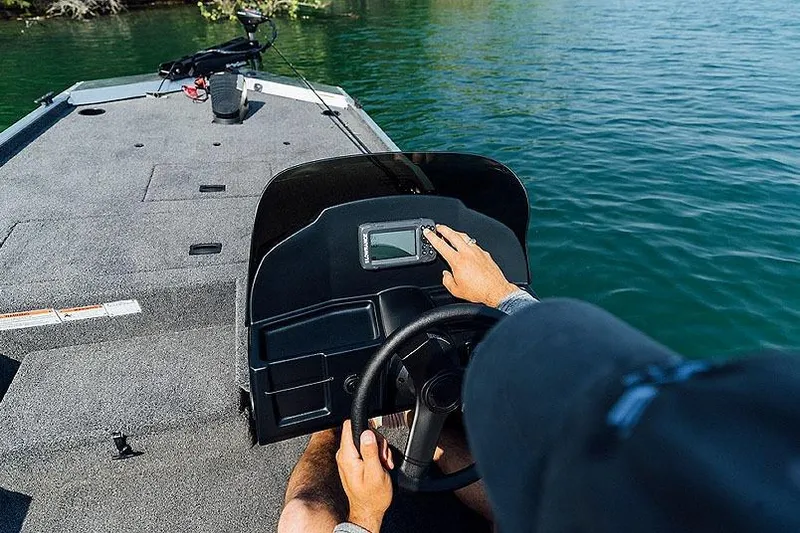 Slide: The Image of Manufacturer Provided Image: Person steering 2026 Lowe Skorpion 16 boat on a lake, adjusting dashboard controls. - 11