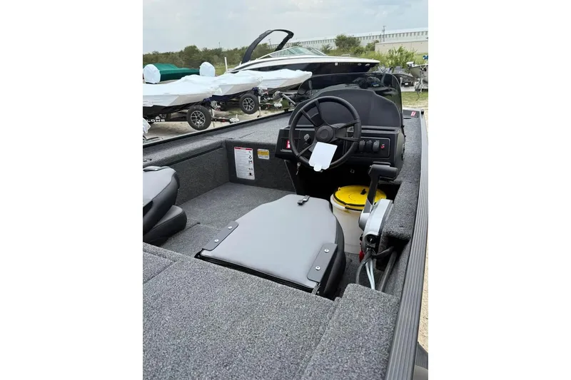 Slide: The Image of 2026 Lowe Skorpion 16 boat interior with steering wheel and seating, parked outdoors. - 6