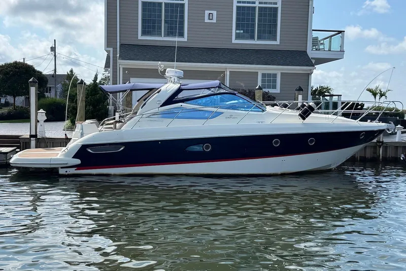 The Image of 2009 Cranchi Mediterranee 43 yacht docked by a waterfront house. - 0