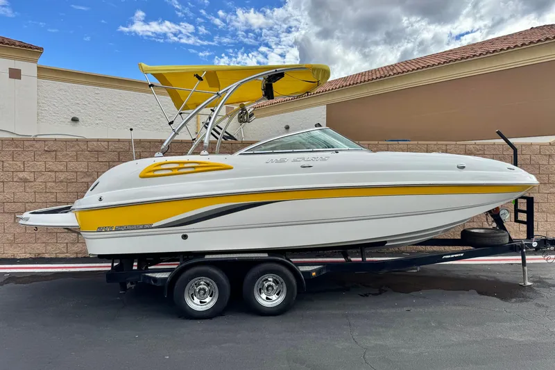 The Image of 2005 MB 240 V Sportdeck boat with yellow accents on a trailer, parked outdoors. - 0
