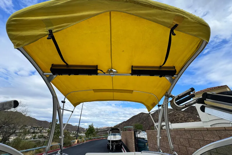 Slide: The Image of 2005 MB 240 V Sportdeck boat with yellow canopy, parked outdoors under cloudy sky. - 15